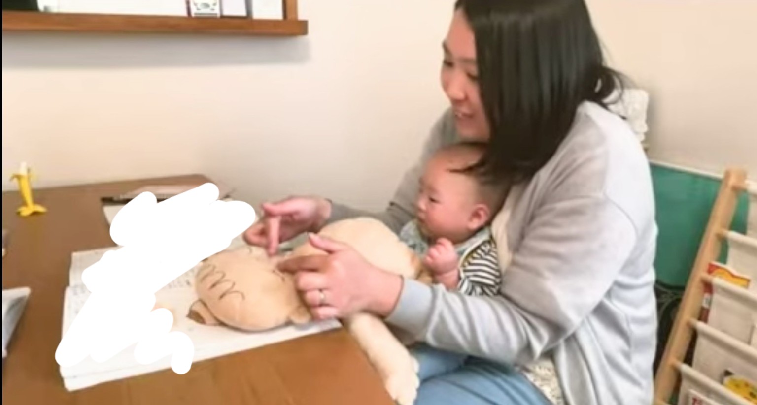 わが子を膝に乗せ、ベビーマッサージ人形を使って学ぶ戸田まいこ