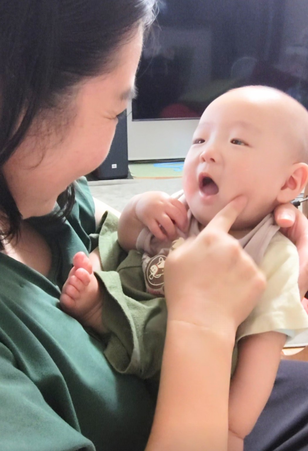 緑の服を着て0歳の息子と向かい合う戸田まいこ